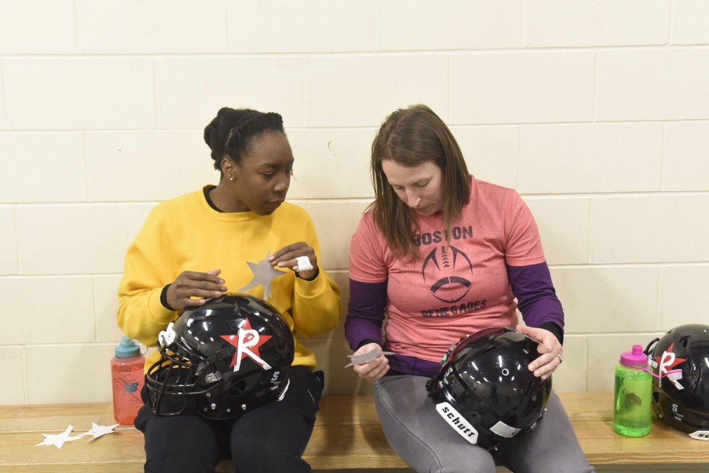 Renegades running back Whitney Zelee (left) and tight end Emily Weinberg (right) work to apply their Renegades logo stickers onto their helmets at their last practice before their home opener, April 16, 2015.(Wicked Local Staff Photo/ Sam Goresh)