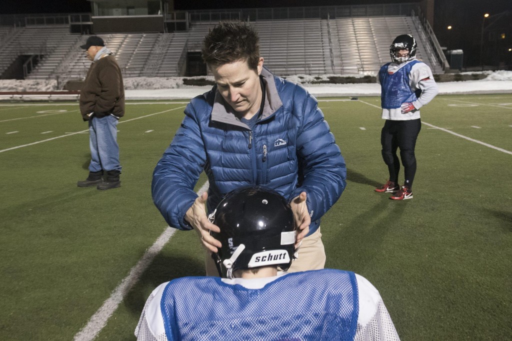 Renegades trainer Michelle Kelley helps a player adjust her helmet so that it fits properly at their practice at Dilboy Stadium, March 23, 2015. (Wicked Local Staff Photo/ Sam Goresh)