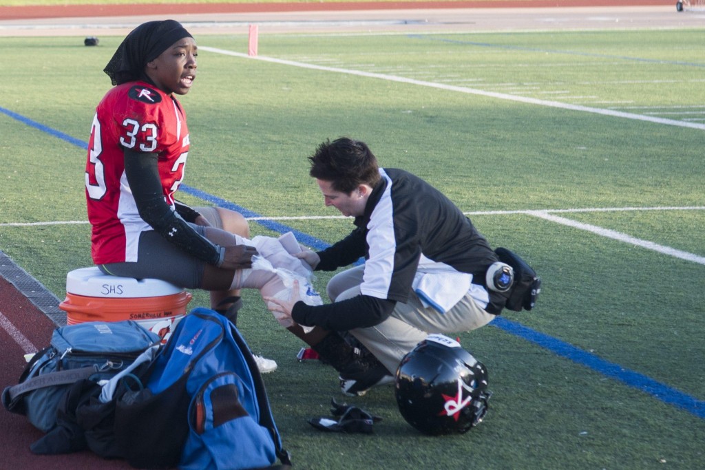 Renegades running back Whitney Zellee cheers for her team as trainer Michelle Kelly wraps her knee in ice in their against the DC Divas at Dilboy Stadium, May 2, 2015. Zelee found out later that she had torn her ACL during a play early in the game. (Wicked Local Staff Photo/ Sam Goresh)